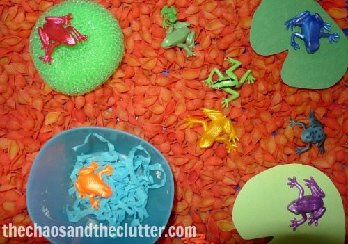red pasta with bright toy frogs and green lily pads in a bin