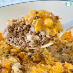 hamburger meat topped with melted cheese on a large spoon