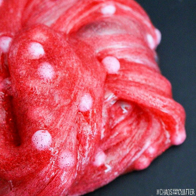 On a black background sits a swirly clump of glittery red slime with white balls that look like polka dots.