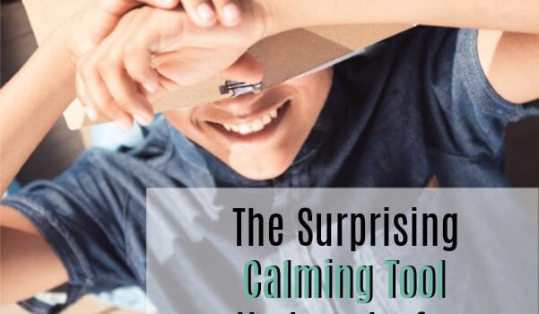 A boy wearing a buttoned up jean shirt lies on his back holding a coil bound notebook over his eyes. He is smiling. The words "The Surprising Calming Tool that works for Older Kids and Teens" is overlaid on the image.