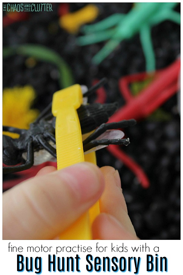 a child's hand shown holding yellow tweezers that are pinching a black plastic bug