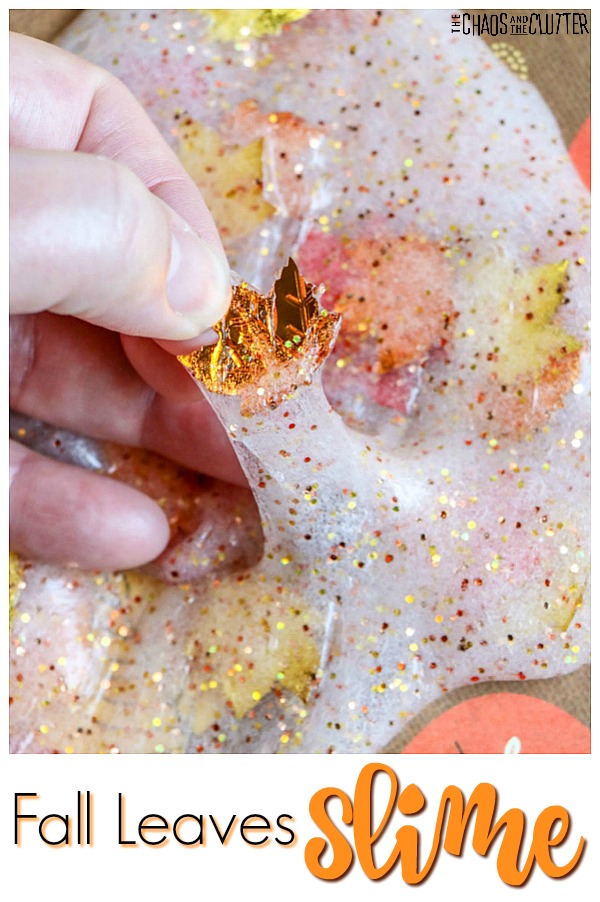 a thumb and pointer finger grab at an orange leaf in a glittery white slime filled with orange and yellow leaves with text that reads "fall leaves slime"