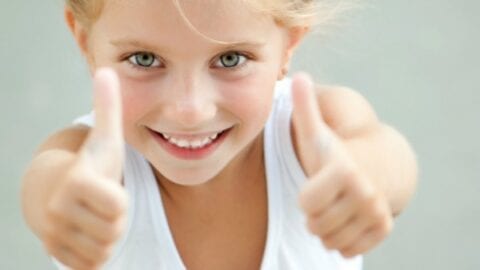 blonde girl in white shirt giving thumbs up sign text reads "Why Kids Need Positive Affirmations"