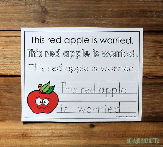 a paper with a sentence to copy "This red apple is worried." and a picture of a red apple.