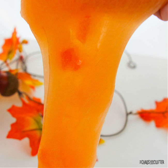 orange slime stretched out with fall leaves in the background