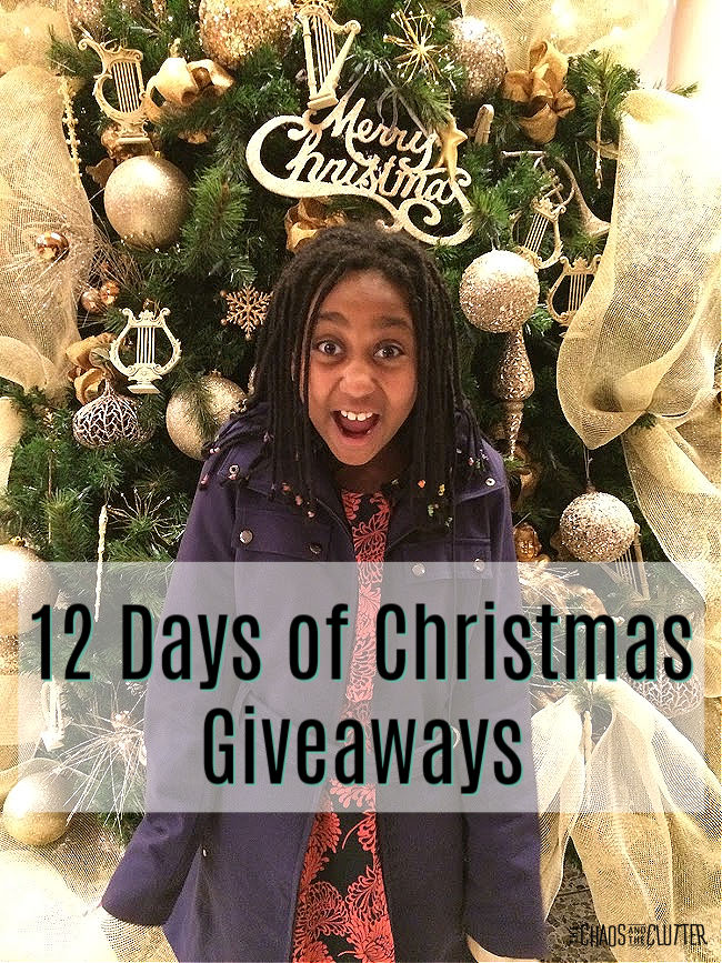 excited girl in purple coat stands in front of a decorated Christmas tree. Text "12 Days of Christmas Giveaways"