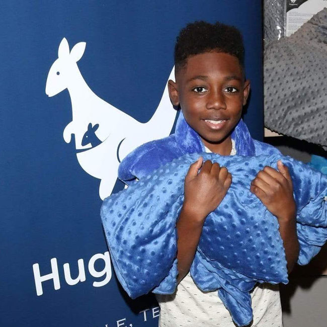 a boy clutches a blue blanket while wearing a blue neck wrap