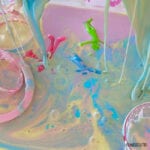 drips of pastel colours of goo coming down into a sensory bin of oobleck