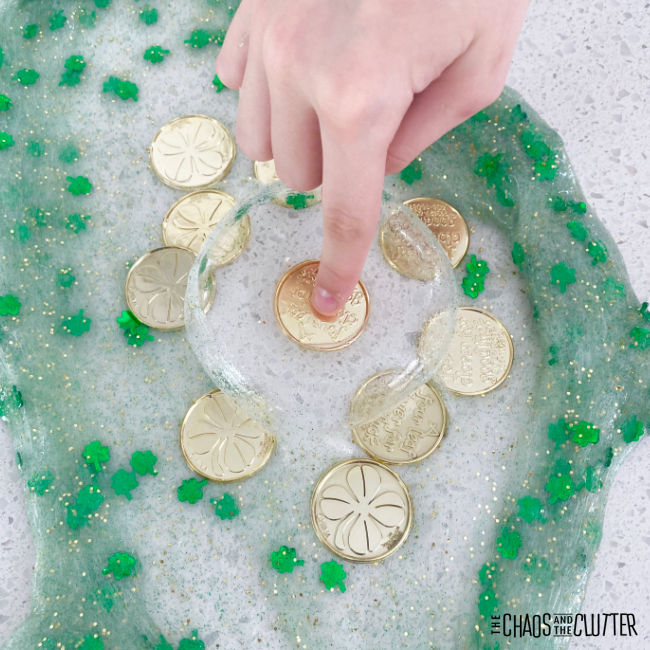 finger presses into an air bubble in shamrock slime to get at a gold coin