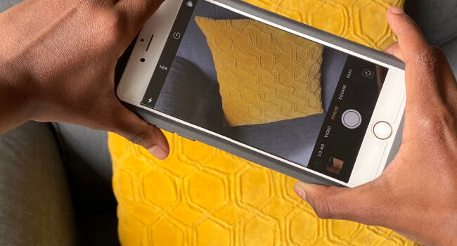 photo of a phone in a child's hands taking a photo of a yellow pillow