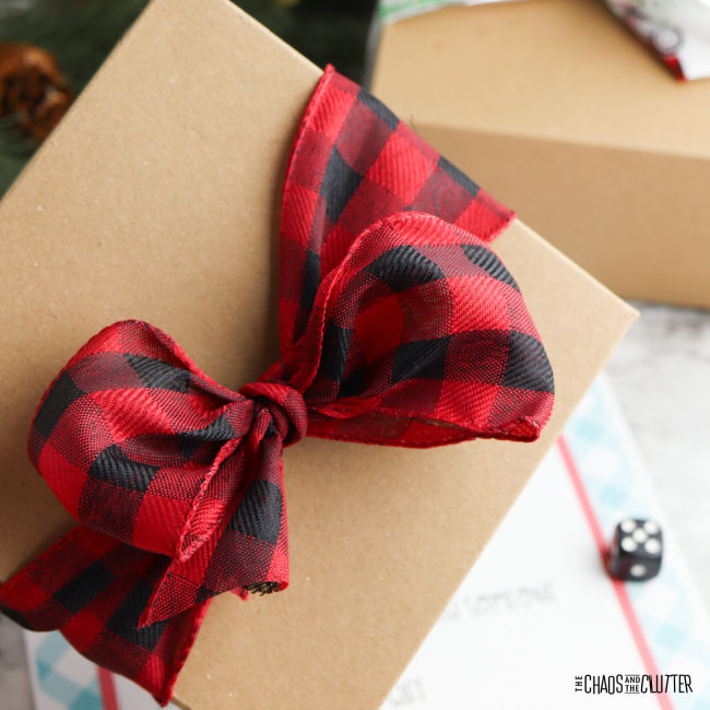 gift with brown paper and a red and black checkered bow. Dice in the background.