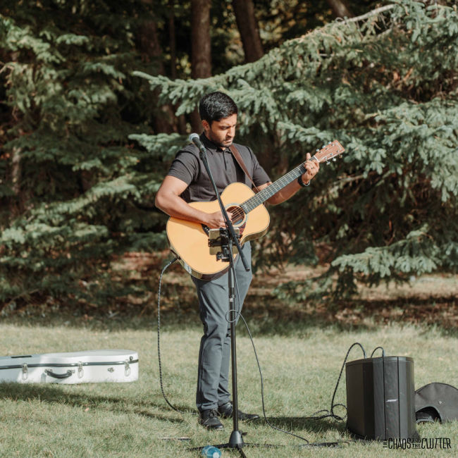 man holding a guitar standing on the grass