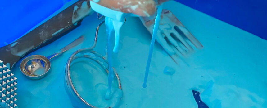 hand scoops up blue goo as it drips from the fingers