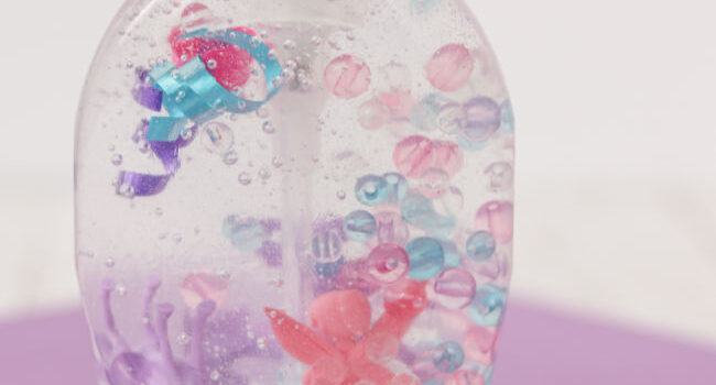 beads, little toys, and ribbon in clear liquid soap