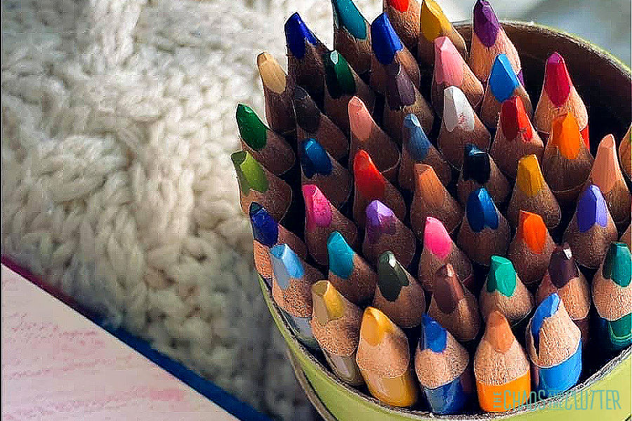 container of colored pencils next to a sweater
